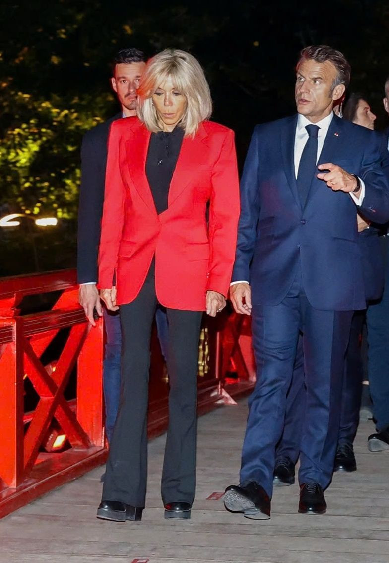 Đỏ - đen là cách phối màu quen thuộc của bà Brigitte Macron. Bà từng mặc set đồ tương tự khi dẫn Hoàng hậu Camilla đến thăm Nhà thờ Đức Bà ở Paris vào năm 2023. Lựa chọn trang phục này phù hợp với những sự kiện nghiêm túc, nhưng vẫn đảm bảo được sự nổi bật. Bên cạnh đó, một số ý kiến đánh giá mặc áo đỏ đến Việt Nam cho thấy sự tinh tế và tôn trọng văn hóa địa phương của Đệ nhất phu nhân Pháp. Theo quan niệm Á Đông, màu đỏ tượng trưng cho sự may mắn và vui vẻ. Ảnh: TTXVN/Getty Images.
