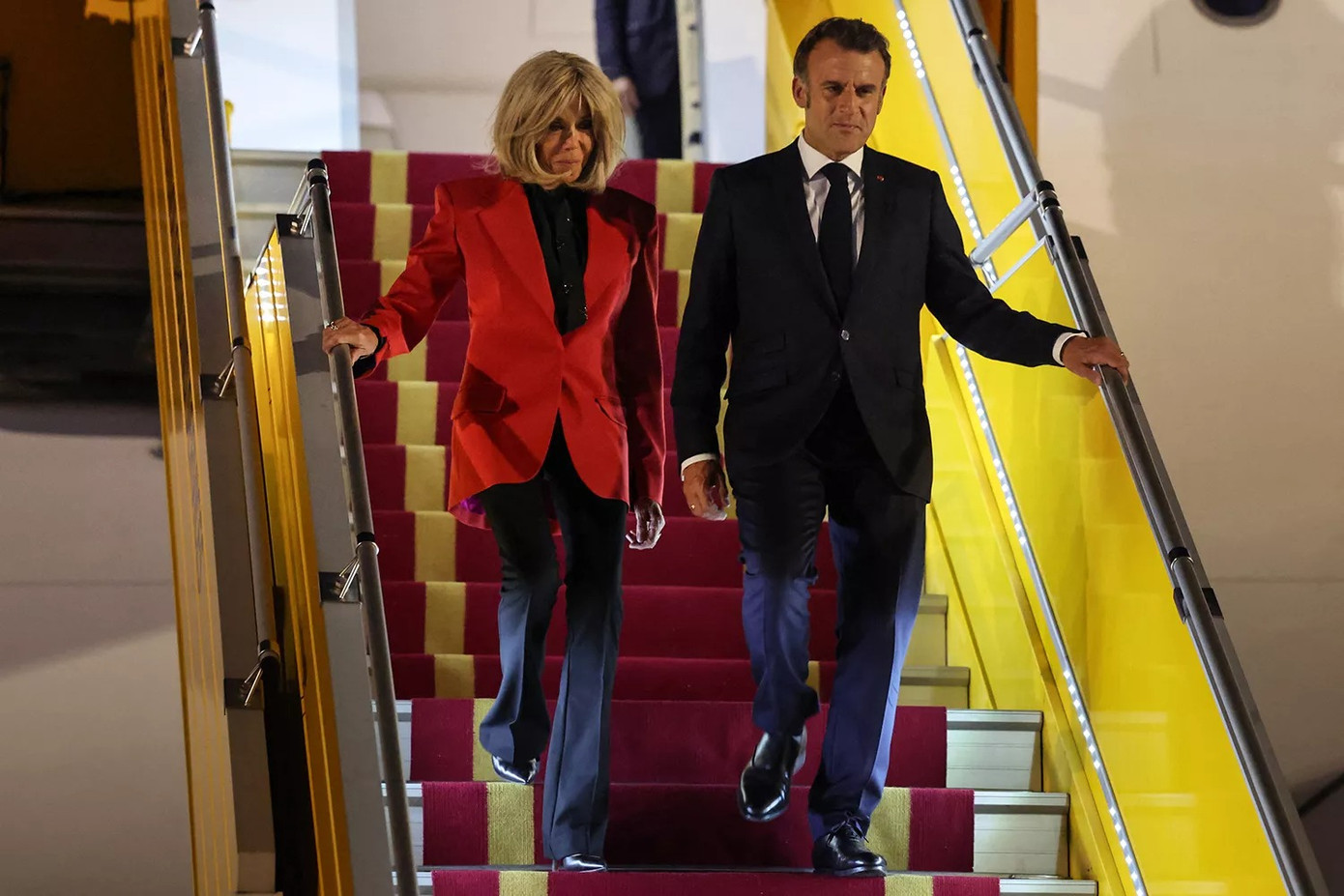 Tối 25/5, Tổng thống Pháp Emmanuel Macron và phu nhân Brigitte Macron đáp máy bay xuống sân bay Nội Bài, bắt đầu chuyến thăm cấp Nhà nước tới Việt Nam từ ngày 25-27/5, theo lời mời của Chủ tịch nước Lương Cường. Thời điểm này, Đệ nhất phu nhân Pháp xuất hiện nổi bật với áo blazer màu đỏ. Ảnh: Getty Images