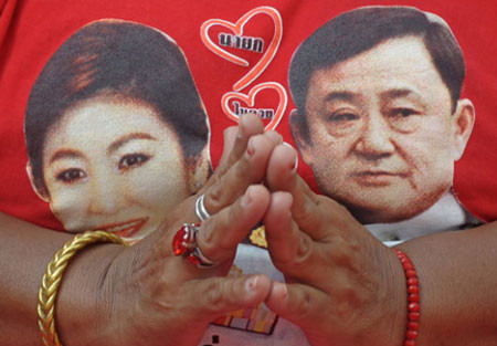 Thủ tướng Thái Lan Yingluck Shinawatra (trái) là em gái của cựu thủ tướng Thaksin Shinawatra. Trong ảnh, hình ảnh hai chính trị gia này xuất hiện trên áo của một người dân thủ đô Bangkok