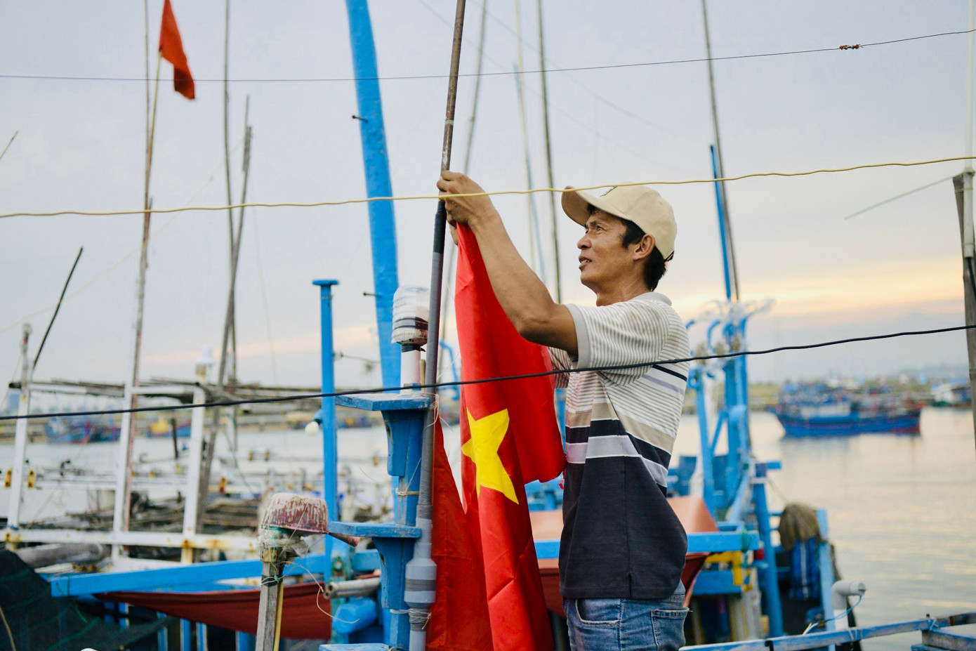 Ngư dân Nguyễn Vinh thay cờ Tổ quốc trên tàu chuẩn bị cho chuyến ra khơi mới. Anh Vinh đã có hơn 20 năm theo nghề biển, với những chuyến xa khơi câu cá ngừ đại dương. Ngư dân Nguyễn Vinh thay cờ Tổ quốc trên tàu chuẩn bị cho chuyến ra khơi mới. Anh Vinh đã có hơn 20 năm theo nghề biển, với những chuyến xa khơi câu cá ngừ đại dương.