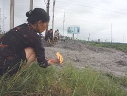 Bà Nguyễn Thị Duyên thắp hương tại nơi mộ chồng bị vùi trong bùn. Ảnh: Thành Lương (Thanh Niên)