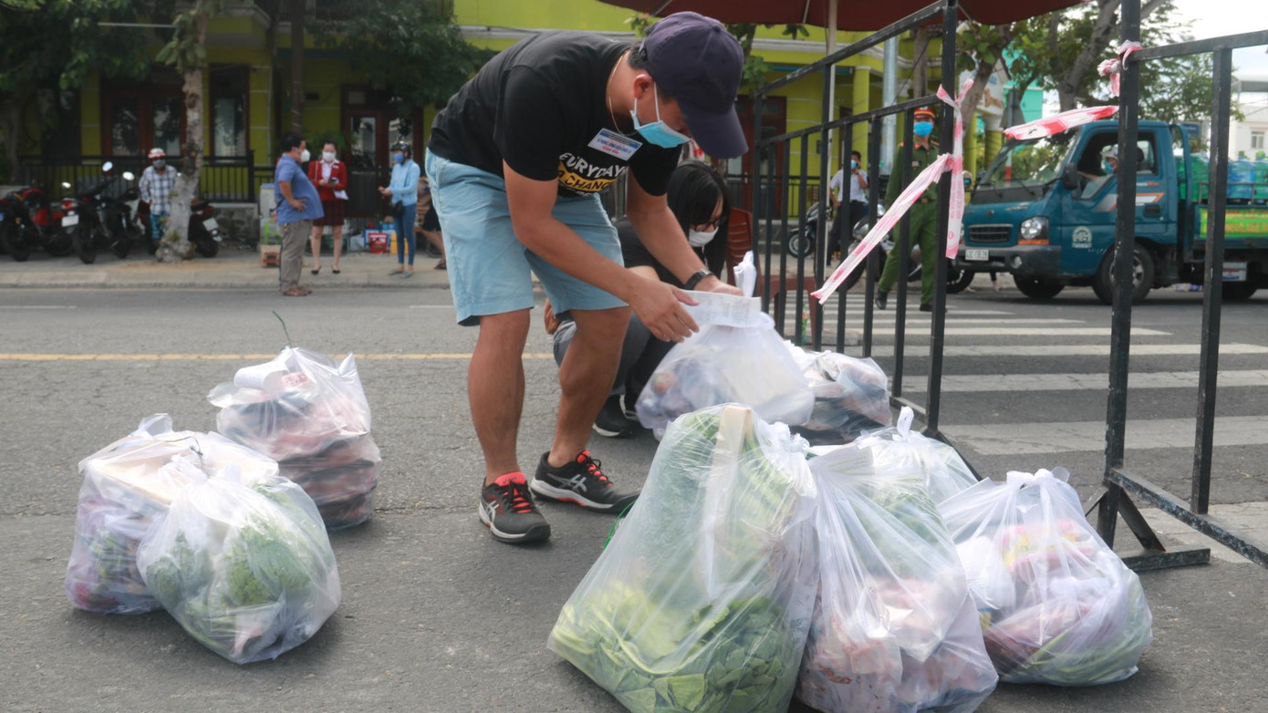 Thành viên tổ COVID-19 cộng đồng thuộc tổ 57 phường Nại Hiên Đông tiếp nhận nhu yếu phẩm tại chốt kiểm soát trên đường Trần Hưng Đạo. Trước đó, người dân trong tổ dân phố nhận danh mục hàng hóa, giá công khai từ nhà cung ứng. Tổ COVID-19 sẽ thực hiện việc giao nhận hàng và đưa đến từng hộ dân.