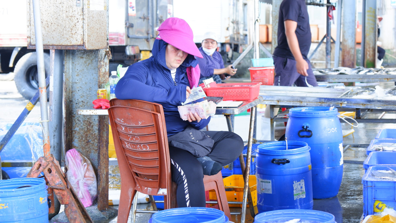 Tiểu thương, chủ tàu thu tiền bán hải sản ngay tại chợ cảng cá Thọ Quang. (Ảnh: Nguyễn Thành)