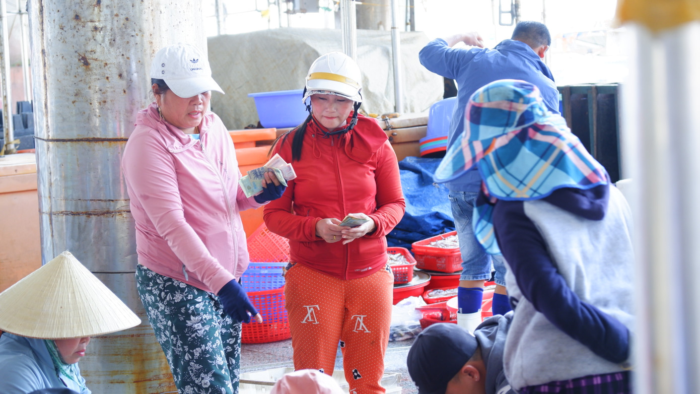 Tiểu thương, chủ tàu thu tiền bán hải sản ngay tại chợ cảng cá Thọ Quang. (Ảnh: Nguyễn Thành)