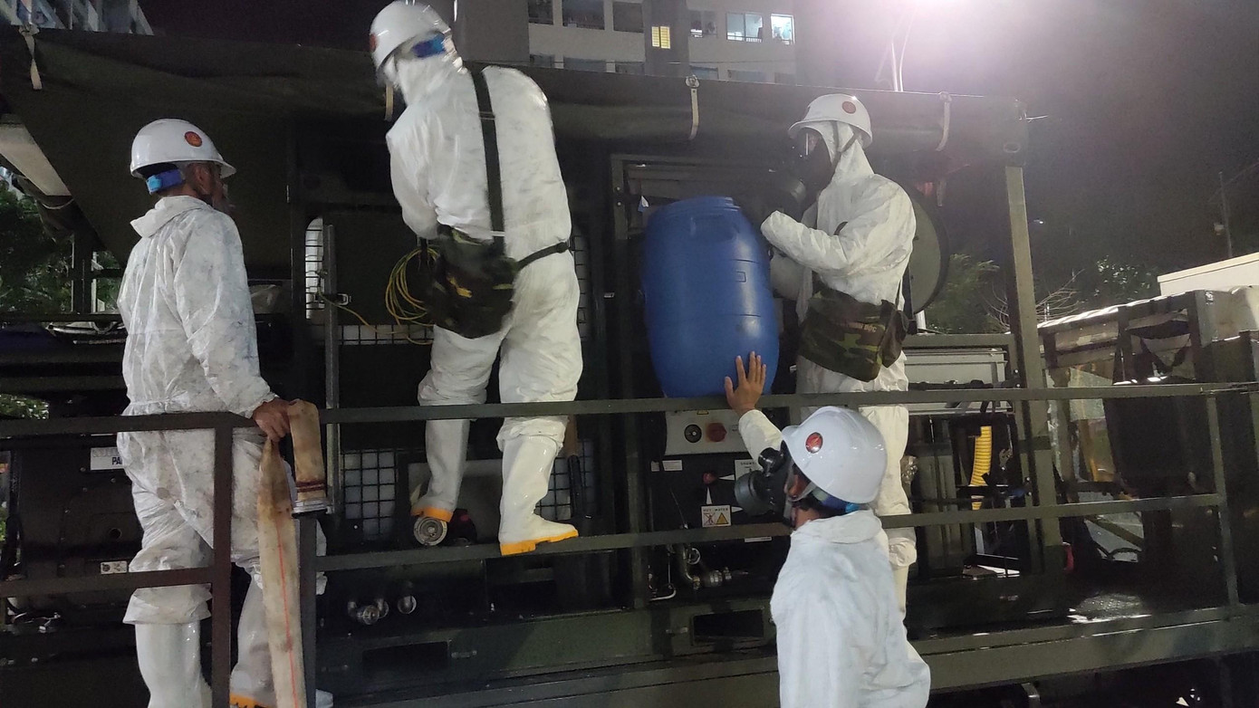 Các cán bộ chiến sĩ tiến hành pha hoá chất Cloramin B dùng để phun khử khuẩn quanh khu vực các chung cư.