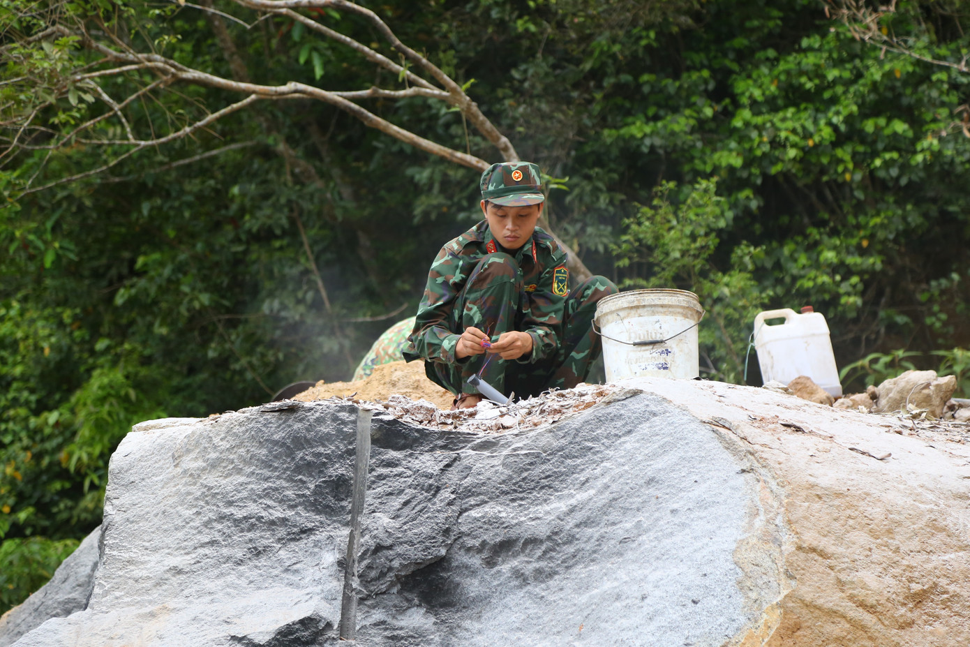 Cẩn thận khoan, nhồi thuốc nổ vào các tảng đá lớn, kích nổ để phá đá.