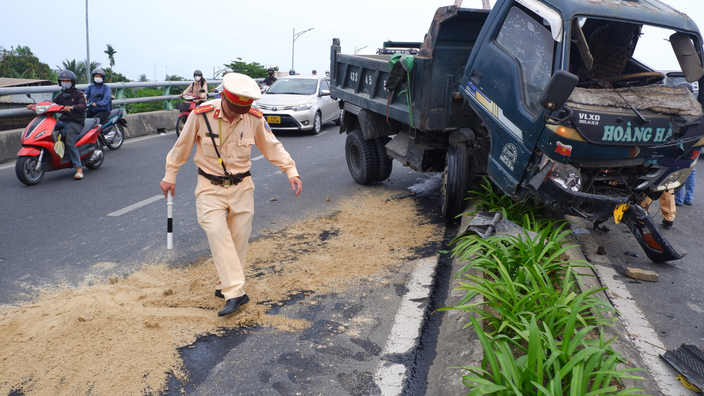 Một chiến sĩ cảnh sát giao thông gạt cát phủ vết dầu chảy trên mặt đường đảm bảo an toàn cho người dân tham gia giao thông.