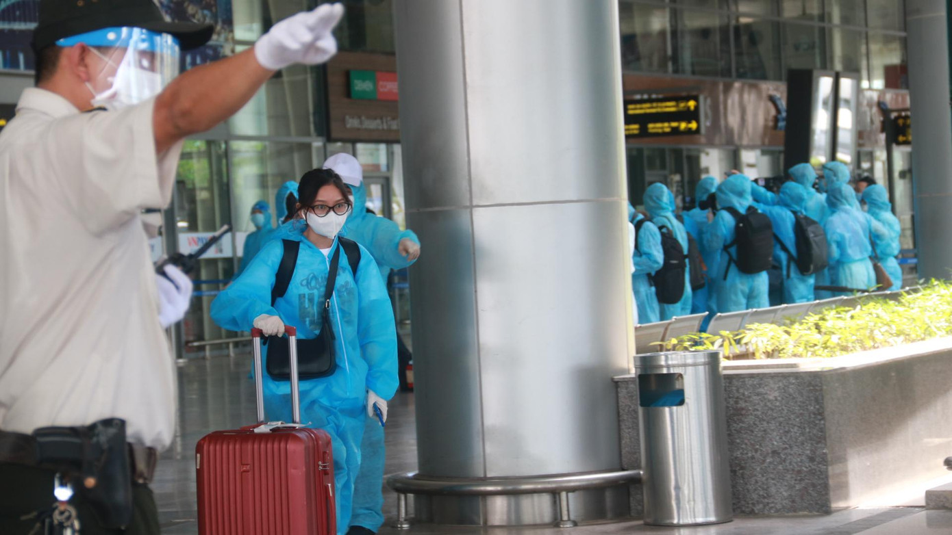 Những hành khách đầu tiên xuống máy bay được hướng dẫn đi theo lối riêng để lên xe. Tất cả đều được mặc đồ bảo hộ. Ảnh: Nguyễn Thành