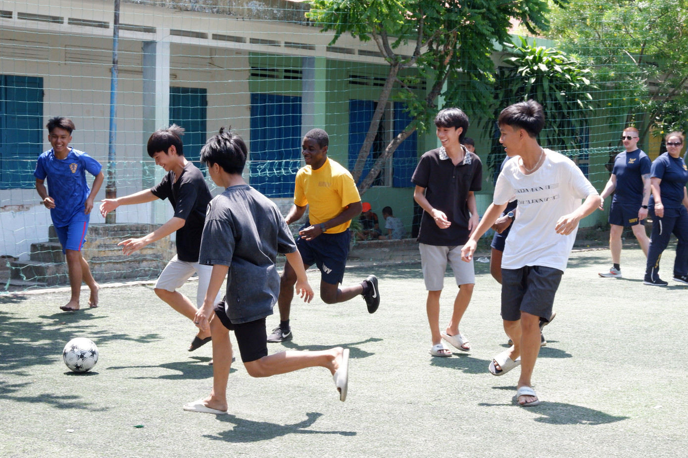 Các thành viên thủy thủ đoàn giao lưu bóng đá với các em nhỏ trong không khí vui vẻ, đầy những tiếng cười vang.