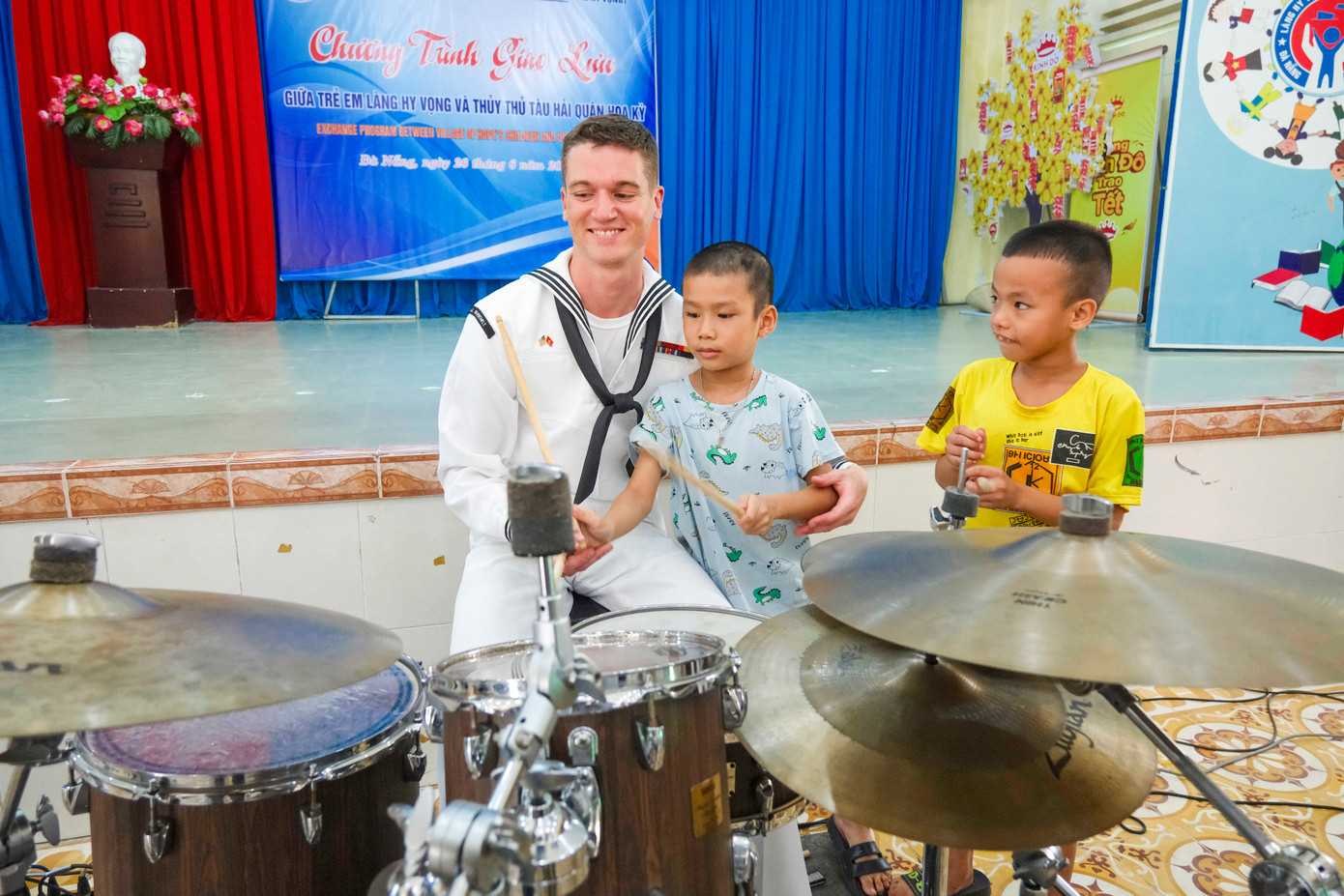 Thành viên ban nhạc chỉ các em nhỏ Làng Hy vọng cách chơi trống. Các hoàn cảnh ở Làng Hy vọng đều là trẻ mồ côi nên chịu nhiều thiệt thòi.