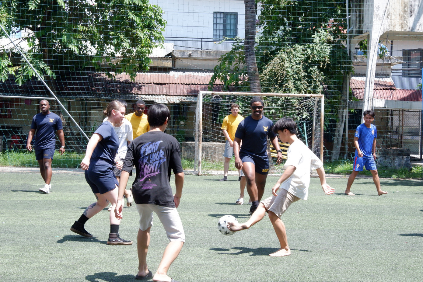 Các thành viên thủy thủ đoàn giao lưu bóng đá với các em nhỏ trong không khí vui vẻ, đầy những tiếng cười vang.