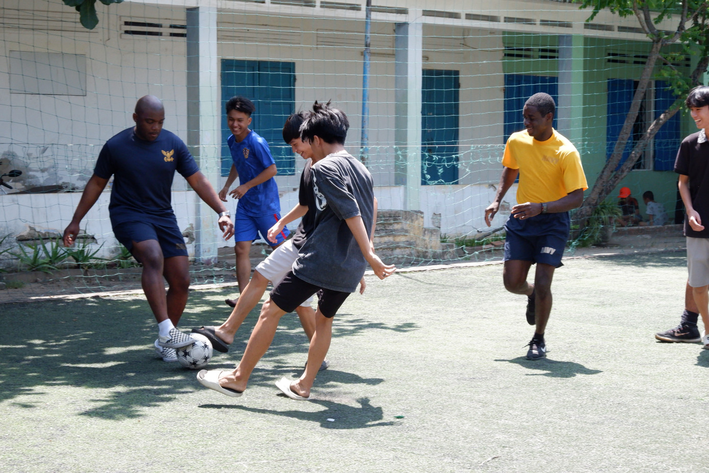 Các thành viên thủy thủ đoàn giao lưu bóng đá với các em nhỏ trong không khí vui vẻ, đầy những tiếng cười vang.