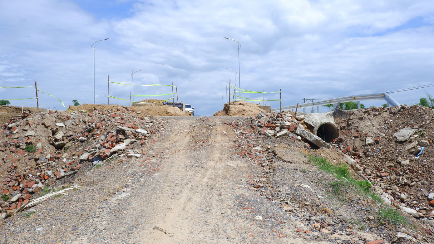 Phần đường dẫn lên cầu chưa thi công, dốc cao, đất đá lởm chởm người và phương tiện qua lại khó khăn, tiềm ẩn nguy cơ mất an toàn giao thông.