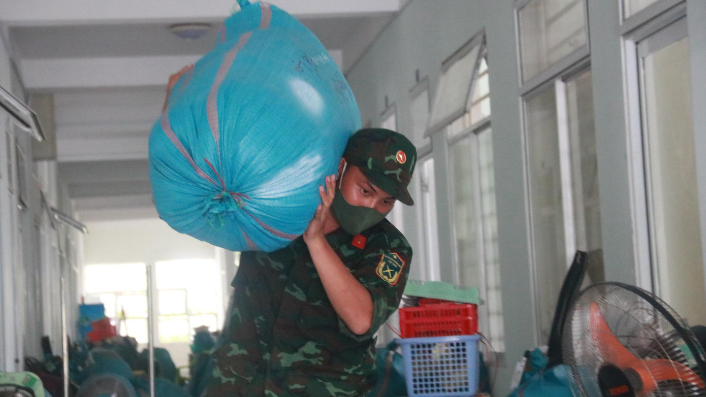 Các chiến sĩ vác từng bao tải lớn chứa đồ đạc của sinh viên bên trong về điểm tập kết, vận chuyển vào kho bảo quản.