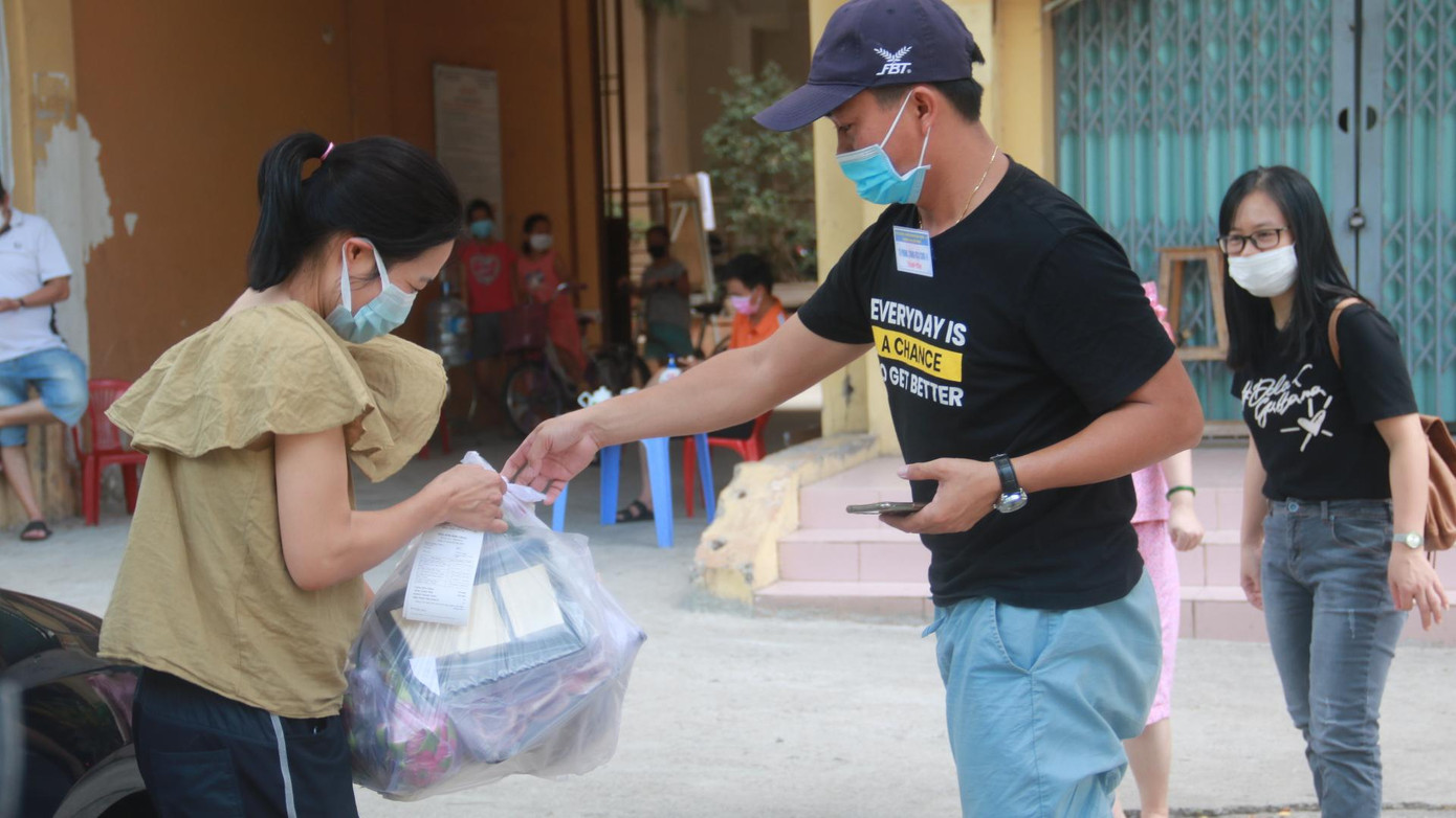 Người dân vui vẻ nhận hàng hóa từ thành viên tổ COVID-19 cộng đồng.