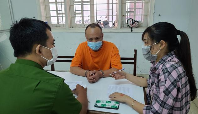 Đồng phạm Wang BaiQiang (áo vàng) tại cơ quan công an.