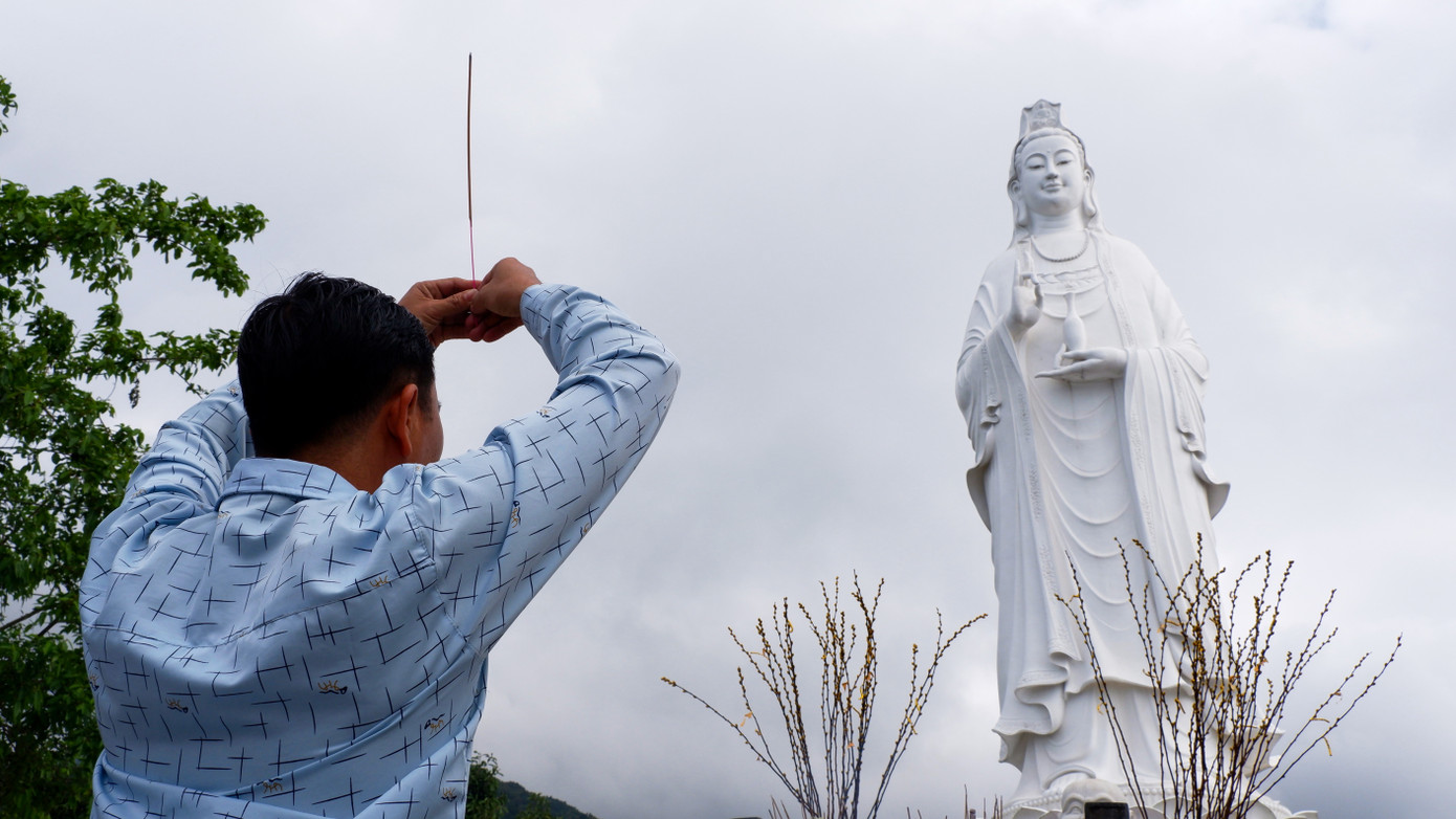 Một người dân Đà Nẵng thành tâm khấn nguyện trước tượng Phật Quan Âm. Với nhiều người dân Đà Nẵng tin rằng tượng Phật Quan Âm tại Chùa Linh Ứng ở bán đảo Sơn Trà rất linh nghiệm. Ảnh: Nguyễn Thành.