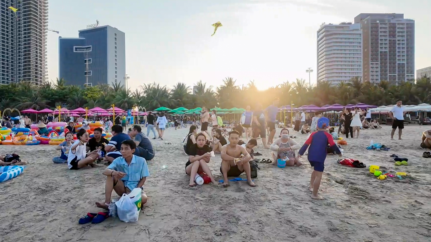 Người dân và du khách ngồi hóng mát, trò chuyện, ngắm biển trong nắng chiều mát dịu ở bãi tắm số 3, khu vực công viên Biển Đông.