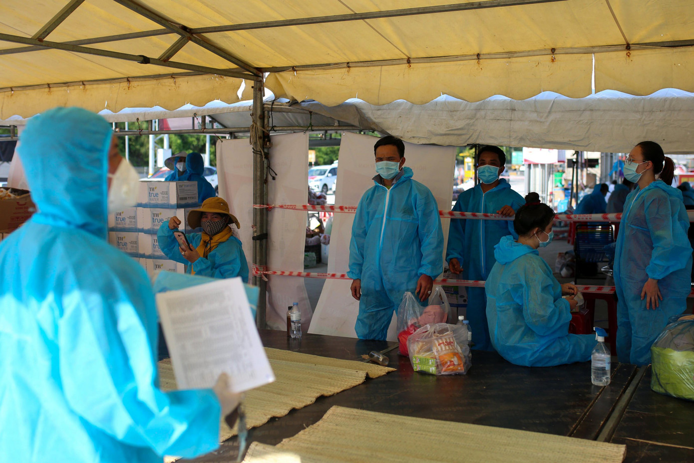 Người dân được phát đồ bảo hộ thực hiện theo hướng dẫn của các tình nguyện viên. Người dân được phát đồ bảo hộ thực hiện theo hướng dẫn của các tình nguyện viên.