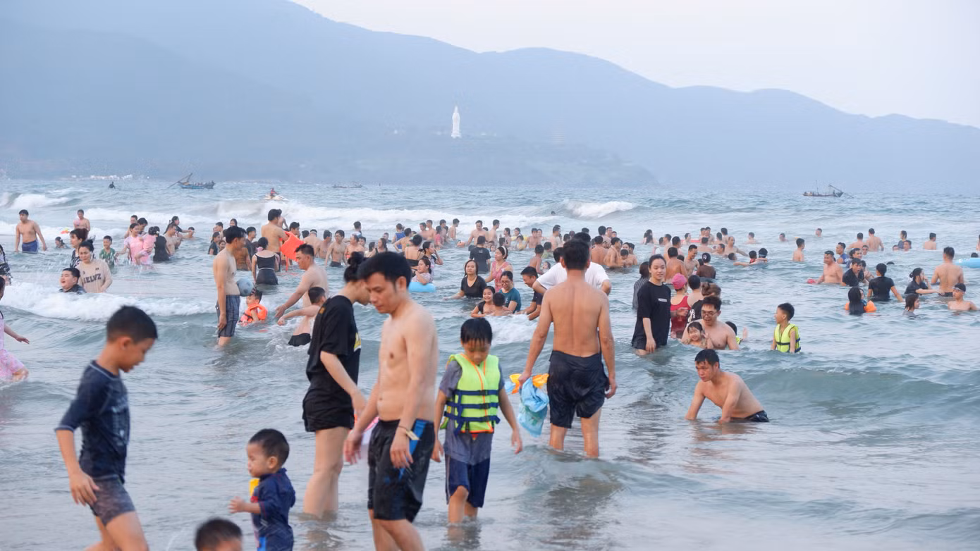 Tại bãi biển số 1, số 2, số 3 ở Công viên Biển Đông, từ khoảng 15h đã có hàng ngàn người dân và du khách kéo về đây để được ngâm mình vào dòng nước mát, giải nhiệt nắng nóng.