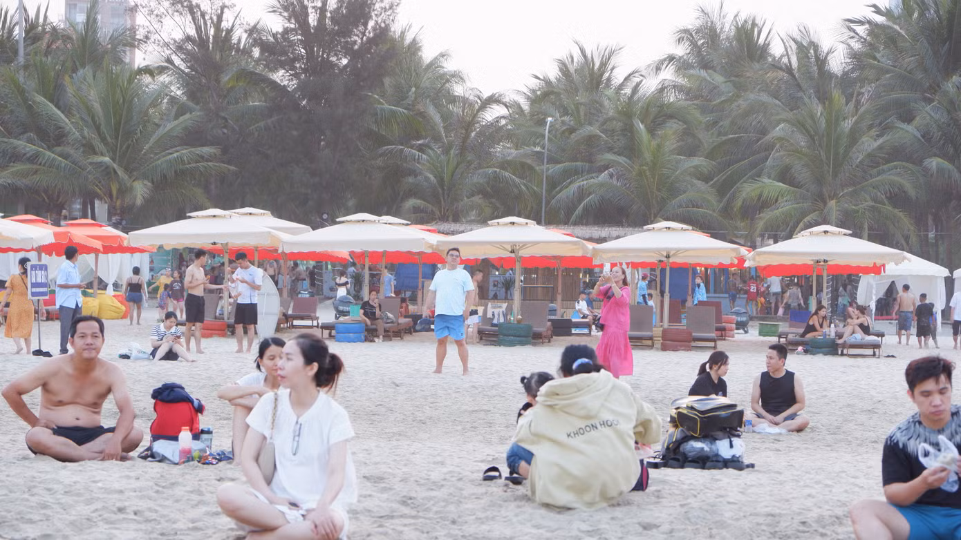 Nhiều người dân và du khách không xuống nước thì chọn cách ngồi hóng mát trên bãi cát trắng.