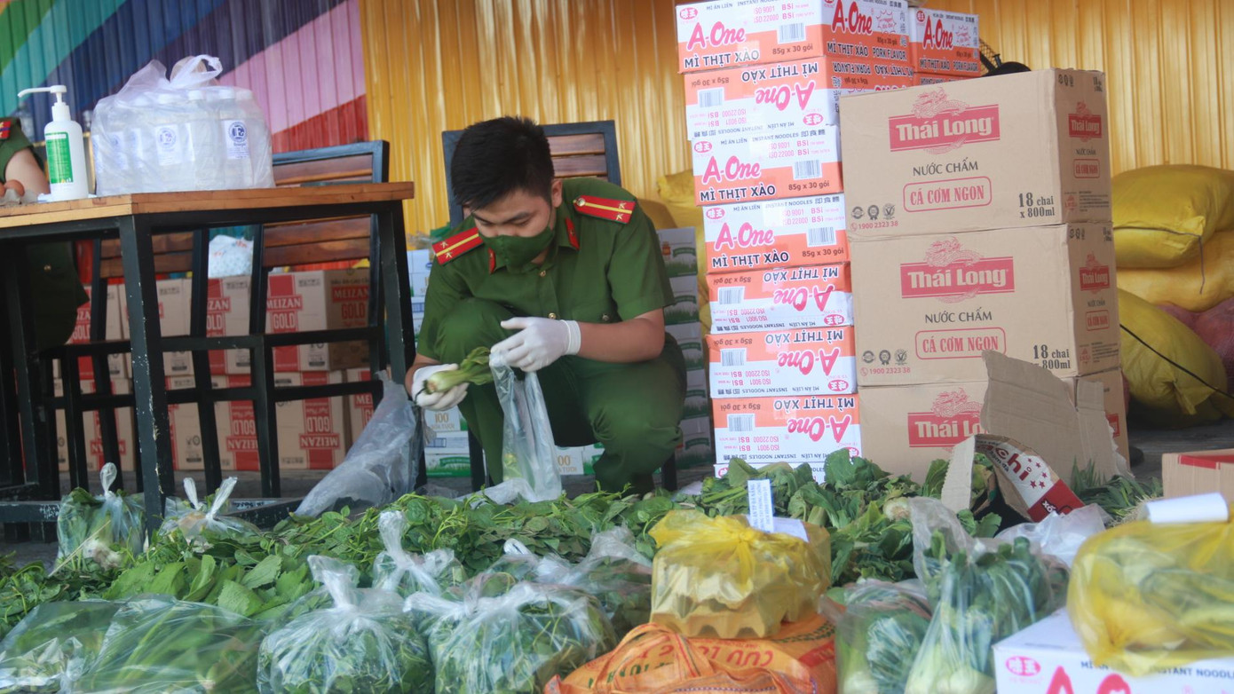 Một chiến sĩ công an nhặt rau, phân thành từng túi nhỏ để tặng kèm các đơn hàng của người dân.