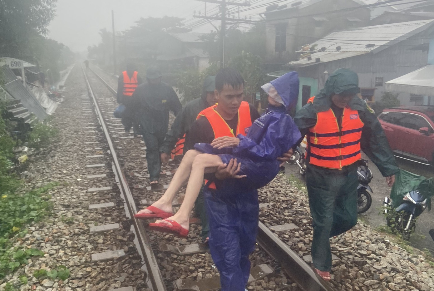 Các cán bộ chiến sĩ bế cụ già lên đường sắt để di chuyển khỏi vùng thấp trũng trong mưa gió. Các cán bộ chiến sĩ bế cụ già lên đường sắt để di chuyển khỏi vùng thấp trũng trong mưa gió.