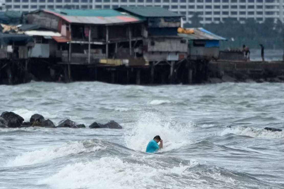 Một cư dân Manila đi bơi bất chấp biển động hôm 23/10. (Ảnh: AP) Một cư dân Manila đi bơi bất chấp biển động hôm 23/10. (Ảnh: AP)