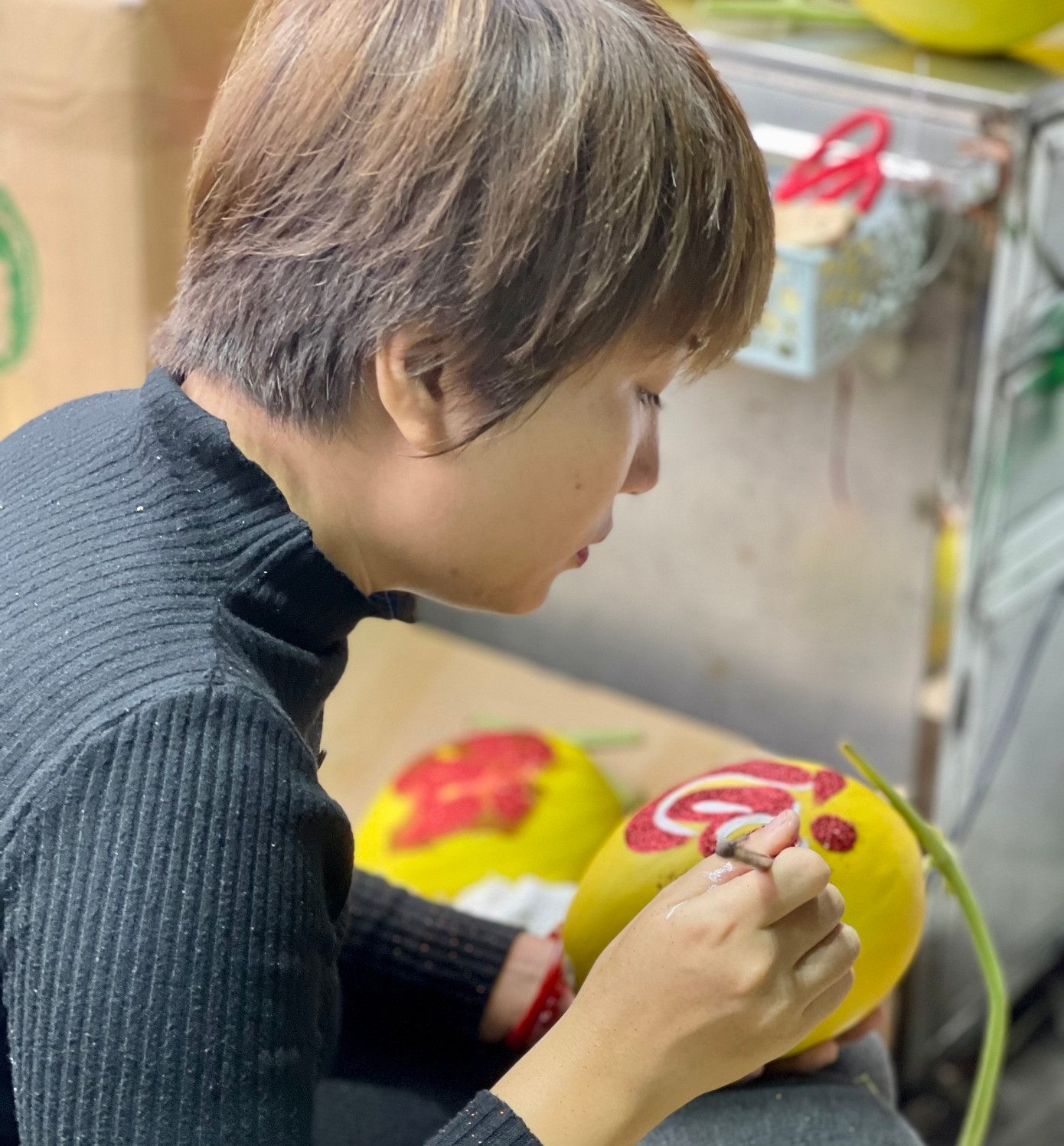 Chị Đào Hà My (30 tuổi) - tiểu thương ở chợ Long Biên tranh thủ lúc không có khách, vẽ thư pháp trang trí dưa gang. "Người Việt có truyền thống bày mâm ngũ quả, thắp hương cúng ông bà tổ tiên ngày tết. Vì thế, những hoa quả được tạo hình, trang trí được nhiều người ưa chuộng; vừa đẹp mắt lại có ý nghĩa cầu may mắn, tài lộc trong năm mới", chị My nói.