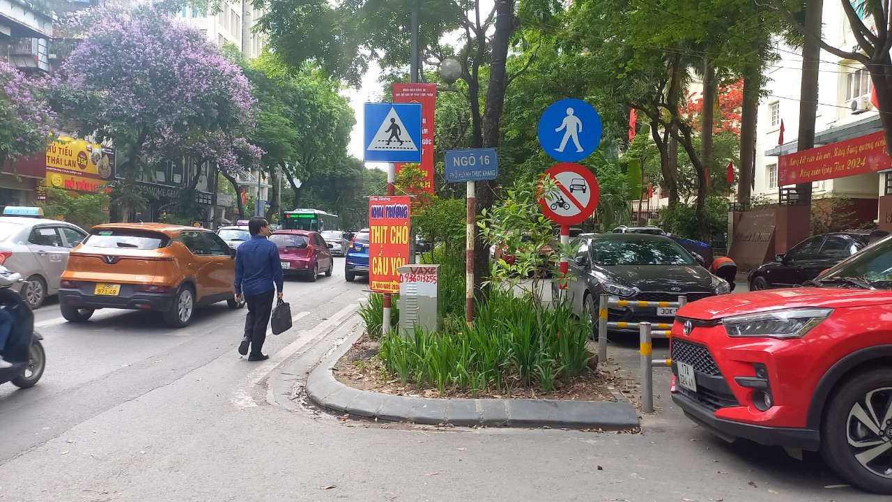 Tương tự, phần đường đi bộ trên hai tuyến phố liền nhau là Huỳnh Thúc Kháng (quận Ba Đình) và phố Thái Hà (quận Đống Đa) cũng trở thành bãi đỗ xe ô tô. Ngay nút ra vào, dưới tấm biển báo đường dành cho người đi bộ cũng bị ô tô đỗ chắn ngang. Người đi bộ phải di chuyển dưới lòng đường.
