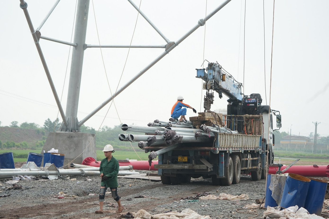 Bên dưới, nhóm công nhân phân loại các thanh, cột, chuẩn bị vật tư trước khi buộc vào dây tời để kéo lên.