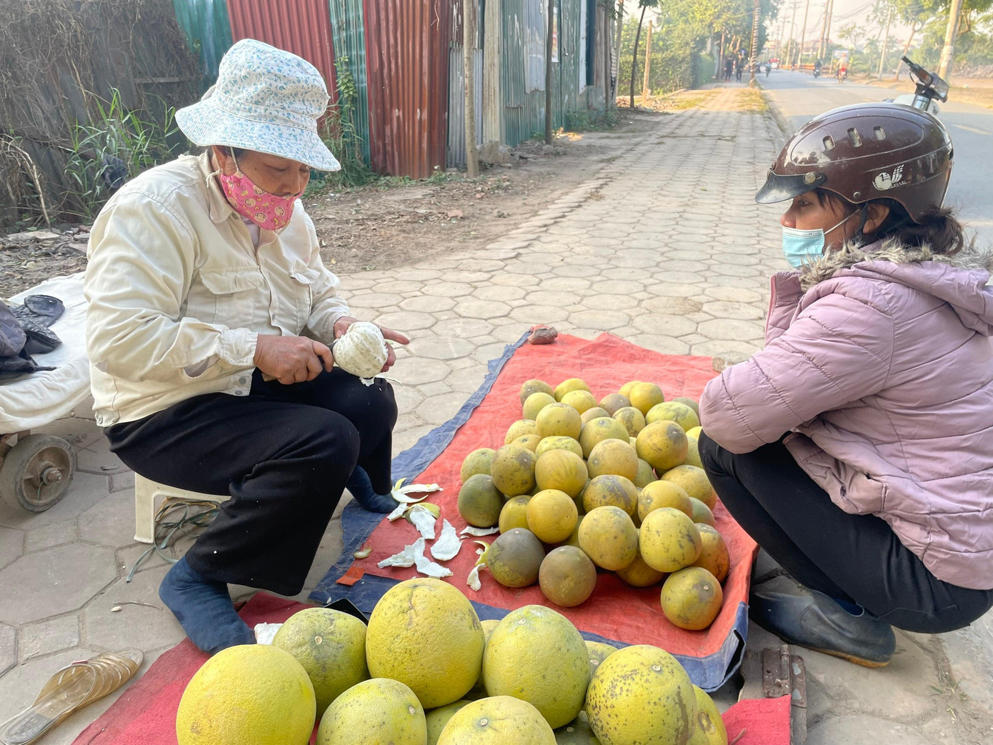 Trên đường Văn Trì, cô Vân, 54 tuổi, bày bán bưởi tháng mười, gọt cho khách ăn thử.
