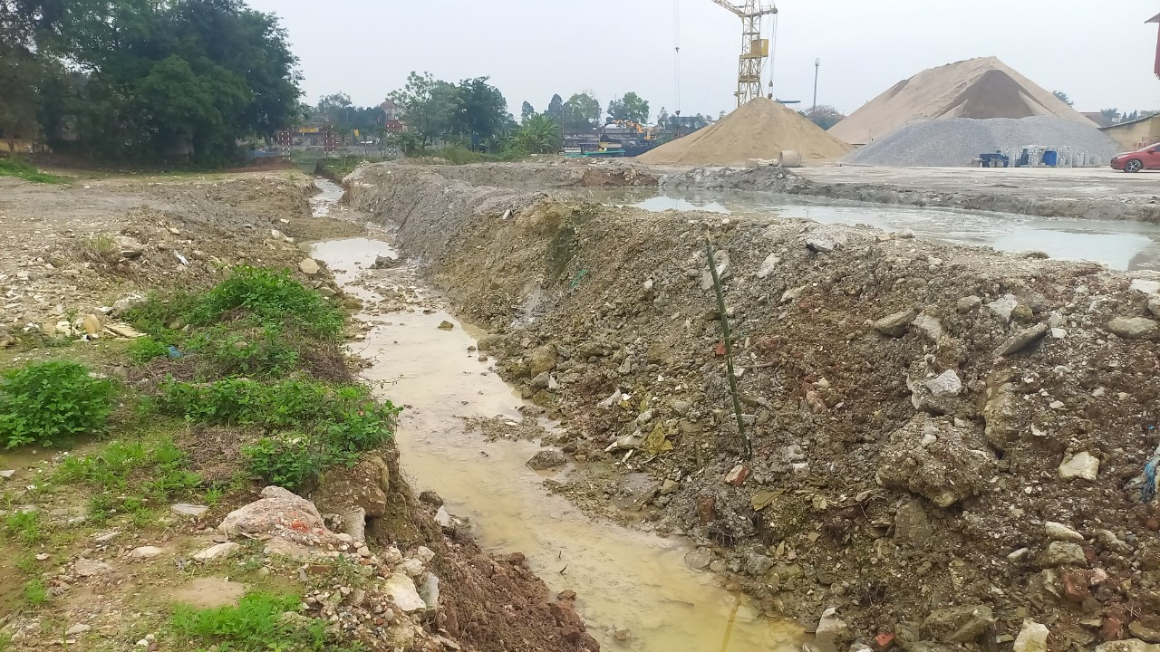 Bên hông của trạm trộn này được đắp một bể chứa thải từ quá trình sản xuất. Trong bể nước thải đục ngầu, xám đen dâng cao tới gần sát mép thành. Váng xi măng sánh đặc, bốc mùi nồng nặc.