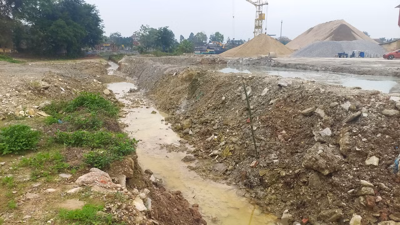 Bên hông của trạm trộn này được đắp một bể chứa thải từ quá trình sản xuất. Trong bể nước thải đục ngầu, xám đen dâng cao tới gần sát mép thành. Váng xi măng sánh đặc, bốc mùi nồng nặc.