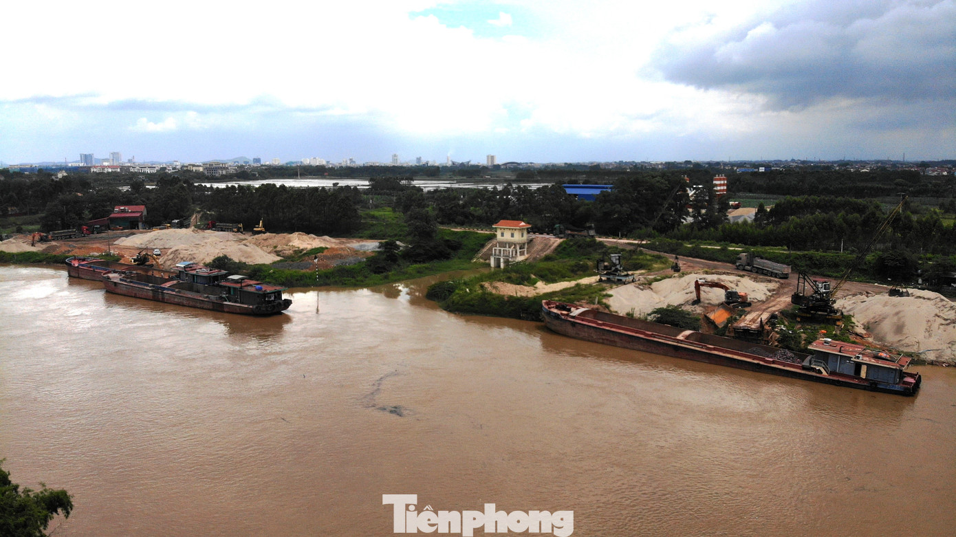 Trên bãi, những núi cát sỏi khổng lồ vẫn nằm “chình ình”. Trên các bãi vật liệu, máy xúc, ủi hoạt động hết công suất, dưới nước tấp nập tàu bè đưa hàng lên bến.
