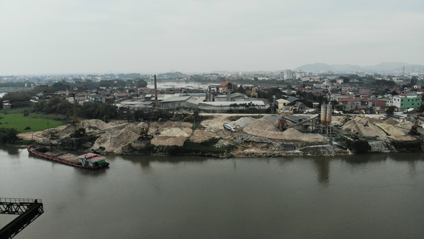 Dưới sông, tàu chở cát, sỏi nối đuôi nhau bốc hàng.