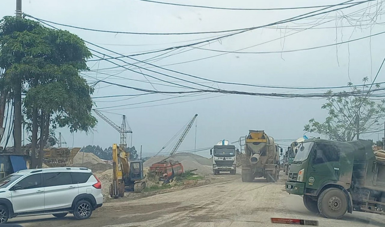 Trên đường đê, xe tải, xe chở bê tông nối đuôi nhau rầm rập chạy. Khói bụi theo các cơn gió mù mịt khắp một khúc đê.