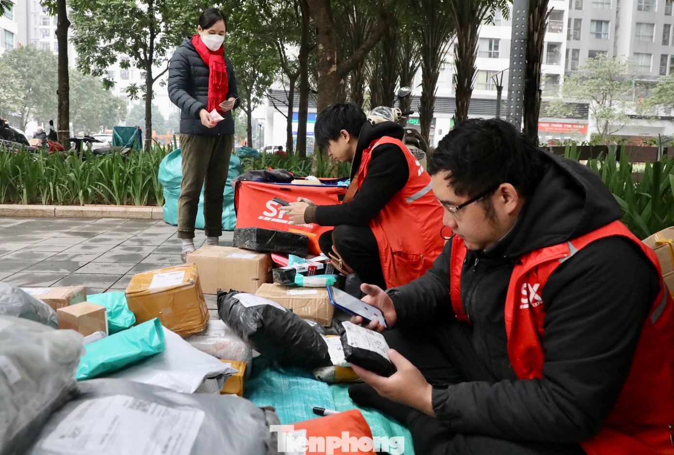 Anh Phan Đại Tài (32 tuổi) cùng bạn đồng nghiệp xếp đơn tại khoảng trống dưới chân chung cư chờ khách xuống lấy hàng. Theo anh Tài, ngày tết, nhiều khi các shiper phải tăng ca để giao đủ đơn hàng cho khách.