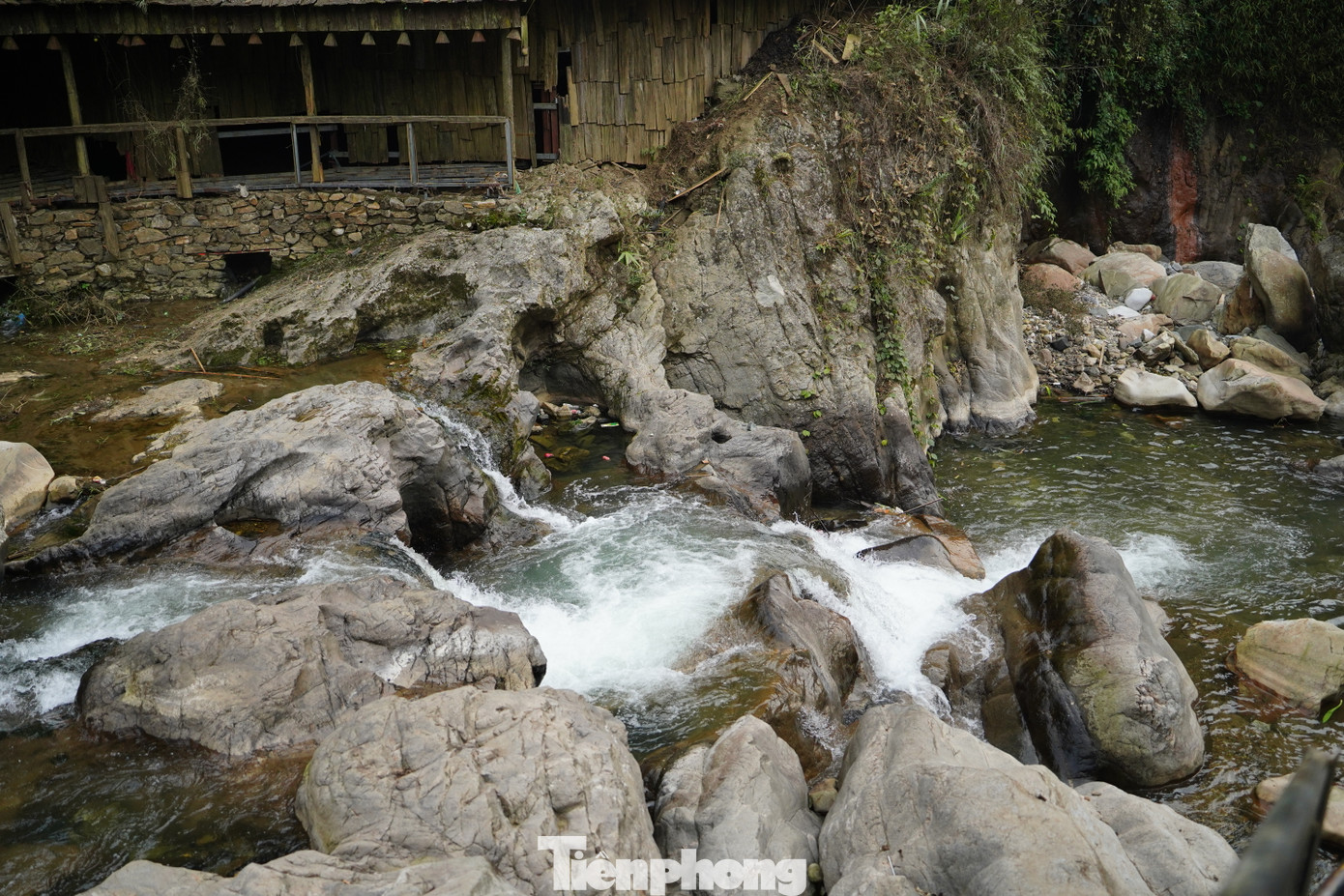 Phía dưới, dòng nước uốn lượn quanh những tảng đá lớn nhỏ, tạo thành những dòng suối nhỏ len lỏi qua bản làng.