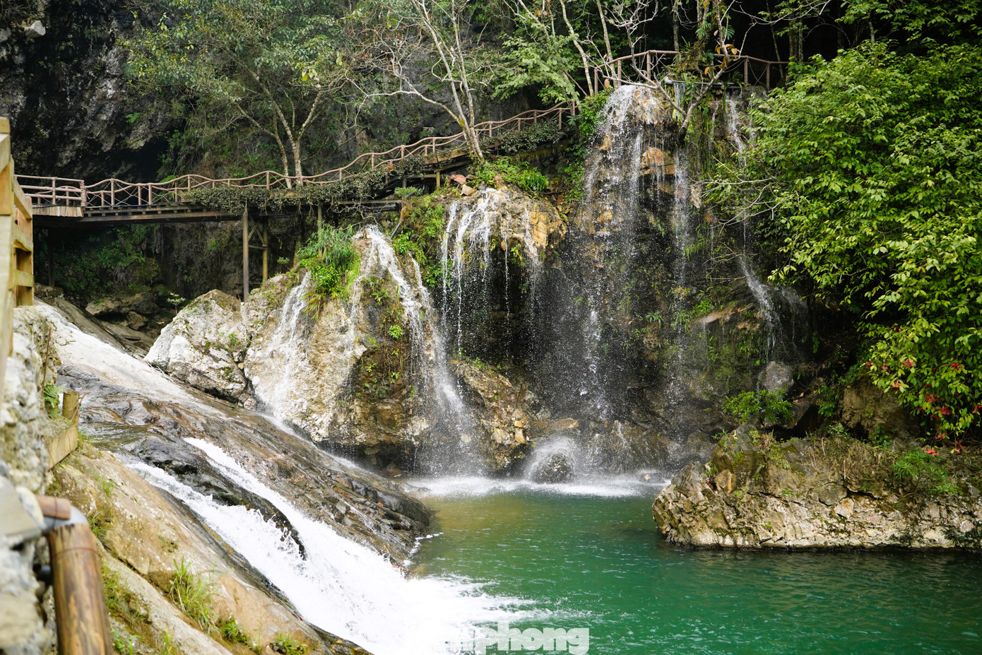 Phía dưới, dòng nước uốn lượn quanh những tảng đá lớn nhỏ, tạo thành những dòng suối nhỏ len lỏi qua bản làng.
