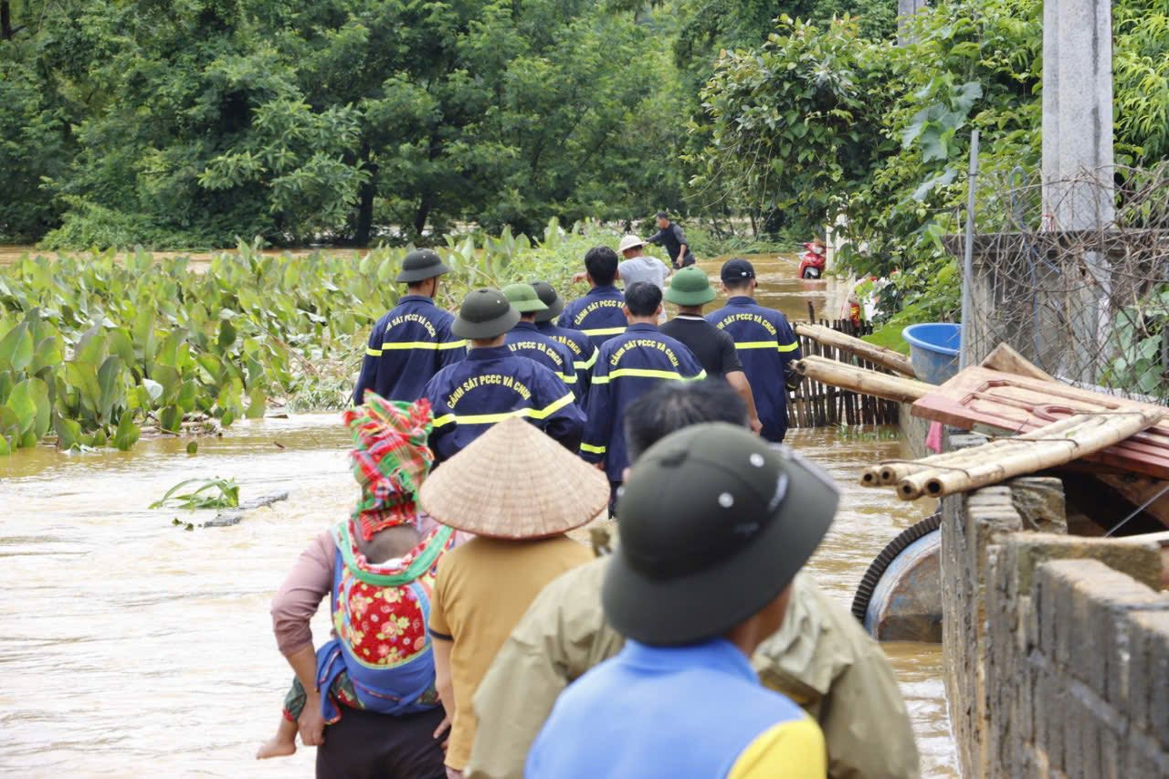 Lực lượng cứu nạn đi vào dòng nước xiết để tìm kiếm, cứu hộ người dân.