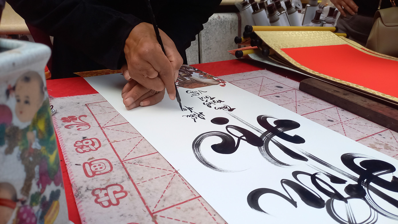 Xin chữ đầu năm cầu may mắn. Mỗi người dân xin những chữ khác nhau như Lộc, Bình An, Tâm... Trong ảnh, thầy đồ đang viết chữ "hiếu học" cho các bạn nhỏ.