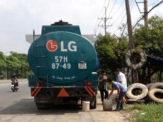 Một tài xế dừng xe ở tiệm vá vỏ để rút dầu ra bán (ảnh chụp trên đường Nguyễn Văn Linh trưa 6-11)