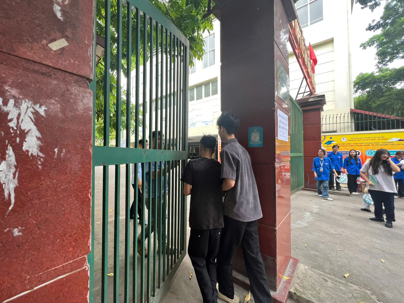 7h32 phút, sau khi có hiệu lệnh phát đề vẫn có 2 thí sinh hớt hải chạy đến điểm thi. Lúc này, cổng trường thi đã đóng, bảo vệ vội chạy ra mở cổng cho thí sinh. Ảnh: Nguyễn Hà