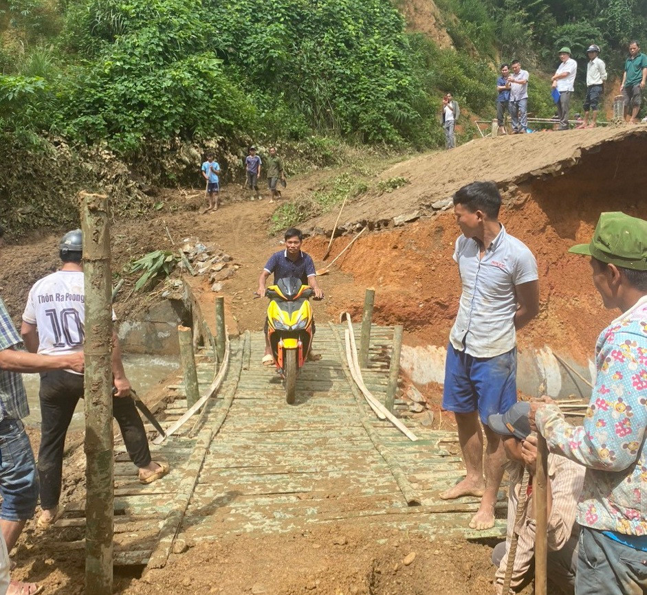 Người dân và lực lượng chức năng dùng vật liệu có sẵn khắc phục để lưu thông tạm thời qua vị trí bị xói lở trên đường tuần tra biên giới Sa Trầm-Pa Lin.