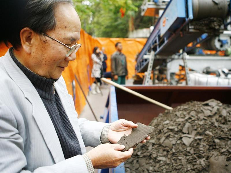 Giáo sư Hà Đình Đức xem và kiểm tra mẫu bùn sau khi được ép thành bánh - Ảnh : Hồng Vĩnh