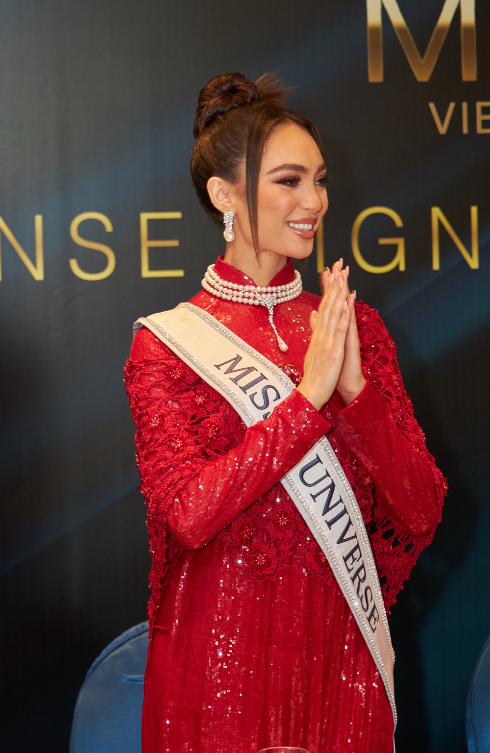 Hoa hậu Hoàn vũ 2022 R'Bonney Gabriel chọn áo dài tông màu đỏ, chất liệu sequin bắt sáng. Điểm nhấn của thiết kế là chiếc áo choàng ren màu đỏ, tăng thêm sự quý phái cho người mặc. Vốn là người đẹp gốc Á, lai Philippines nên R'Bonney Gabriel được khen mặn mà, duyên dáng khi mặc áo dài truyền thống Việt Nam.