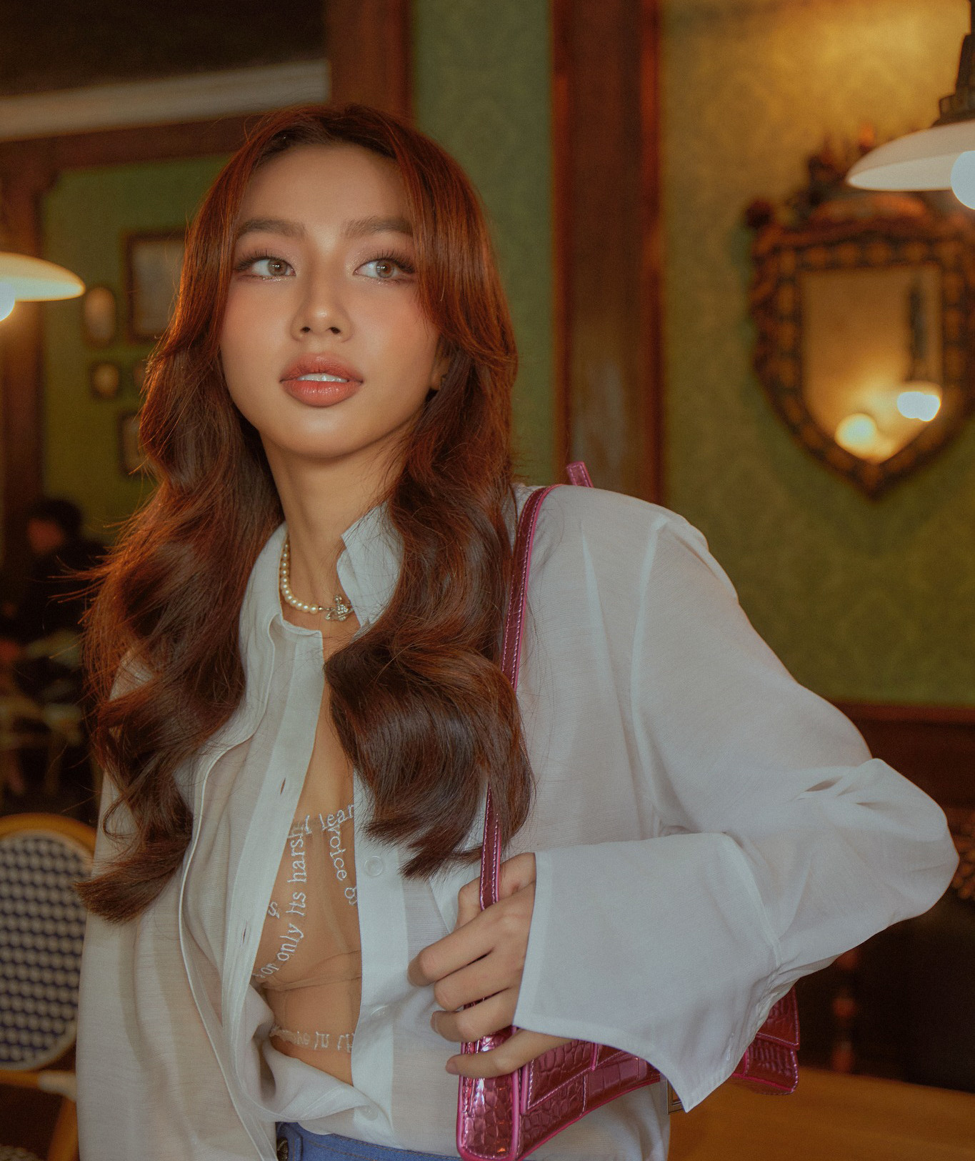 Thùy Tiên mang đến sự phá cách khi kết hợp áo sơ-mi trắng cùng chân váy chất liệu denim. Điểm nhấn của set đồ là đôi boots màu xanh có kiểu dáng lạ mắt. Người đẹp táo bạo khi thả cúc áo nhưng tinh tế chọn áo lót họa tiết bên trong để không hớ hênh.