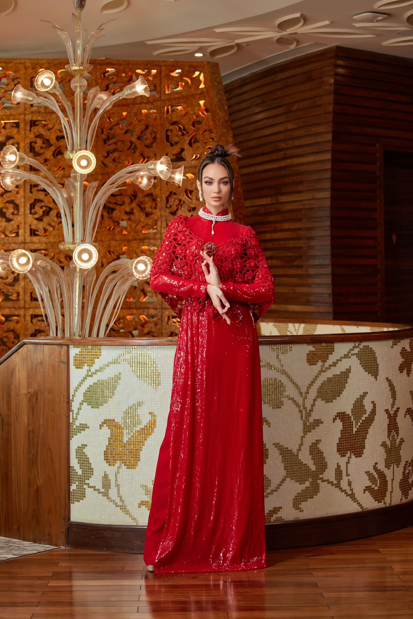 Hoa hậu Hoàn vũ 2022 R'Bonney Gabriel chọn áo dài tông màu đỏ, chất liệu sequin bắt sáng. Điểm nhấn của thiết kế là chiếc áo choàng ren màu đỏ, tăng thêm sự quý phái cho người mặc. Vốn là người đẹp gốc Á, lai Philippines nên R'Bonney Gabriel được khen mặn mà, duyên dáng khi mặc áo dài truyền thống Việt Nam.