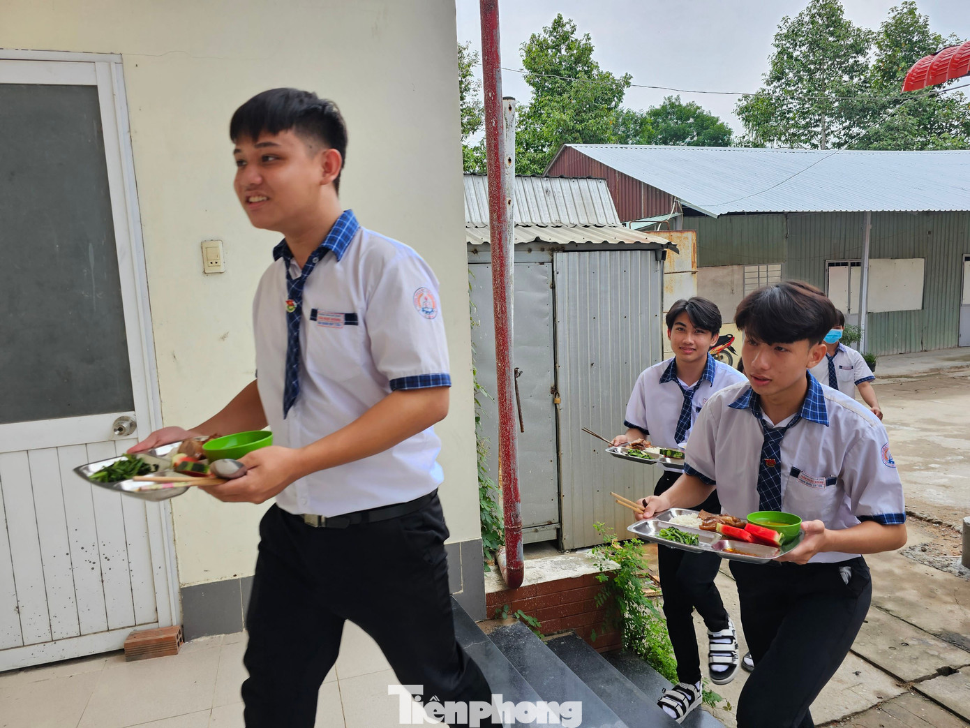 Các em học sinh mang cơm vào địa điểm tập trung trong Nhà thi đấu đa năng để ngồi ăn. Ảnh: Hòa Hội